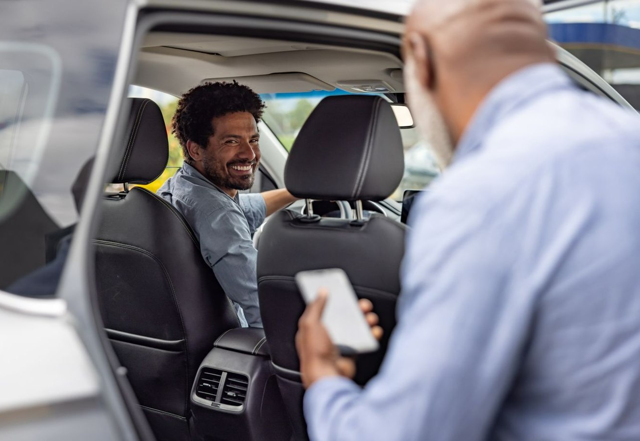 A driver greeting a rider and checking the app before a trip